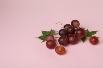 Red ripe grape on pink background, space for text