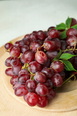 Wooden tray with grape on white textured background