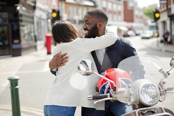 Affectionate young couple hugging at motor scooter on sunny urban street