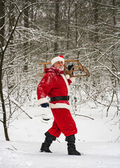 Christmas holiday, active lifestyle. Cheerful Santa Claus holds a sleigh in his hands and walks bravo through the winter snow-covered forest.