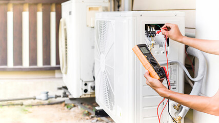 Air conditioner repairman using electricity meter to check air conditioner operation, maintenance...