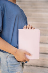 Kid girl in blue t-shirt standing and holding notebook in hands