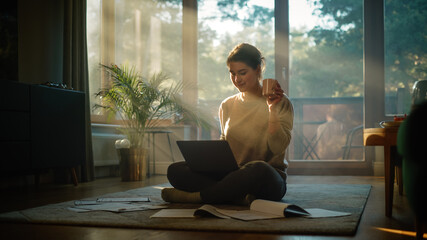 Young Woman Using Laptop at Home Does Remote Work. Beautiful Girl Sitting on the Floor Uses...
