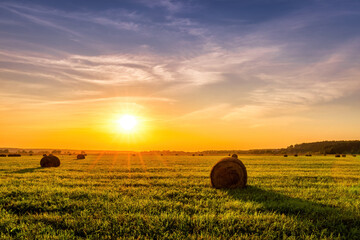 A field with haystacks on a summer or early autumn evening with a cloudy sky in the background....