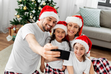 family, winter holidays and christmas concept - happy mother, father and two daughters in santa...