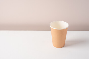 Paper craft coffee cup on white table with beige wall background Minimalism concept