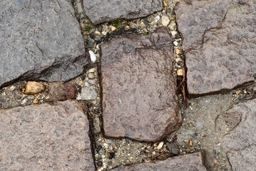 old pavement made of weathered stone blocks close-up