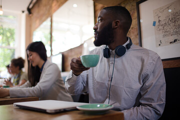 Fototapeta premium Young man with headphones drinking coffee in cafe
