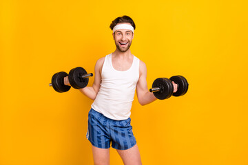 Portrait of attractive cheerful sportive guy lifting weight doing physical work out isolated over bright yellow color background