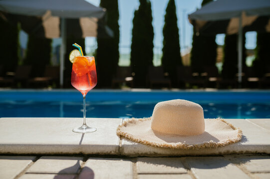 Beverage in glass and hat at the edge of the pool