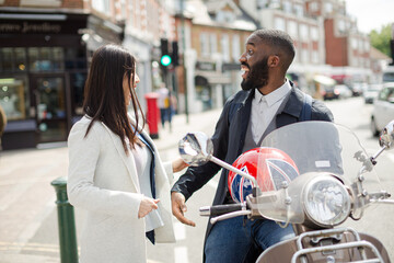 Affectionate young couple hugging at motor scooter on sunny urban street