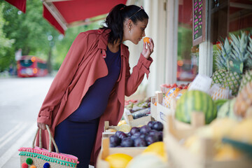Pregnant woman shopping for produce at market storefront