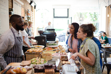 Male worker helping female customers in cafe