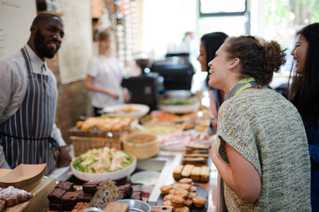 Male worker helping female customers in cafe