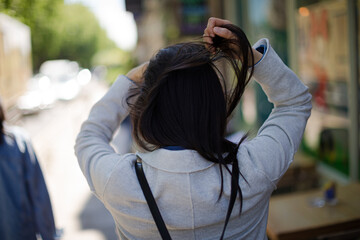 Young woman walking down urban street and playing with her hair