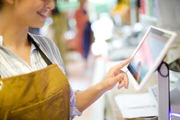Female cashier using touch screen cash register in grocery store