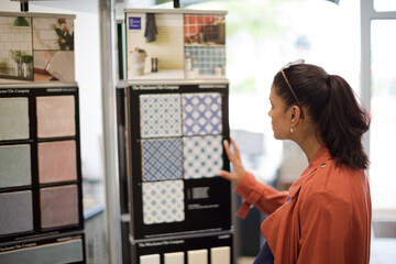 Fototapeta na wymiar Woman browsing tile samples in home improvement store