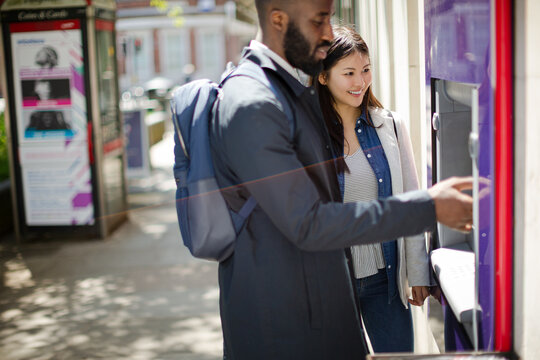 Young Couple Using Urban ATM