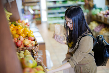 Smiling young woman shopping for apples in grocery store