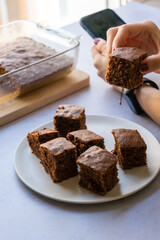 girl using mobile while eating a brownie