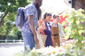 Obraz premium Female florist helping friends at sunny flower shop storefront