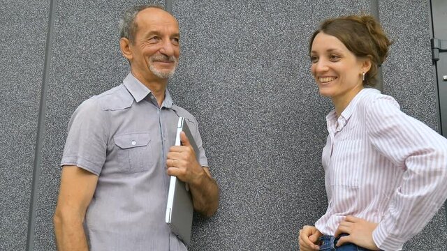 Two business people high-five each other celebrating the success of their project. Colaboration between older coworker and young colleage