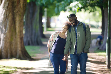Fototapeta premium Young couple holding hands, walking in park