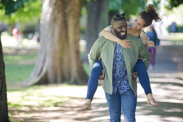 Playful young couple piggybacking in park