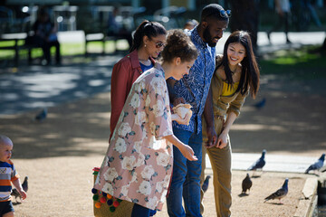 Fototapeta premium Friends feeding ducks and geese at sunny park pond