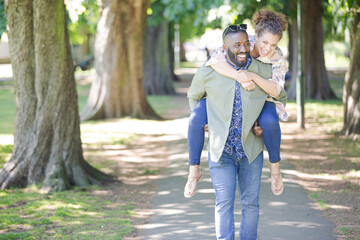 Fototapeta premium Playful young couple piggybacking in park