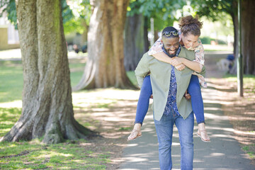 Playful young couple piggybacking in park