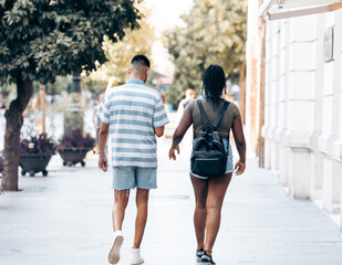 Backs of a man and woman walking through a street