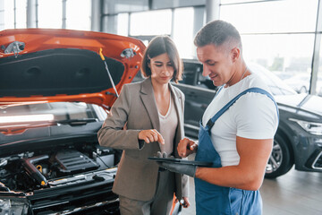Fototapeta na wymiar With female customer. Man repairing woman's automobile indoors. Professional service