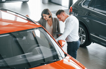 View from above. Man in formal wear helping customer with choice of the automobile