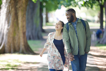 Obraz premium Young couple holding hands, walking in park