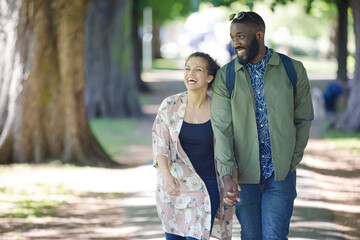 Young couple holding hands, walking in park