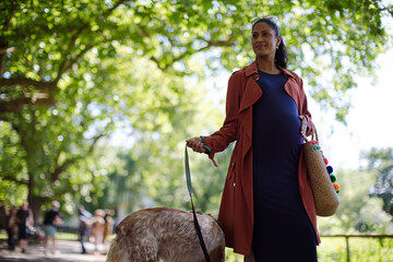 Pregnant woman walking dog in park