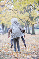 Senior man carrying woman on his back in autumn park