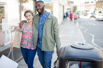 Affectionate young couple with shopping bag outside storefront