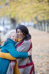 Enthusiastic senior women friends hugging in autumn park