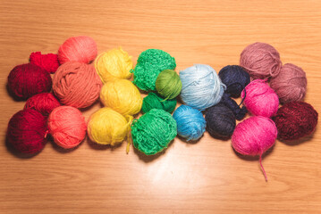 Ovillos de lana con los colores del arcoíris, de diferentes tamaños sobre un fondo de madera. Crochet, ganchillo. Bolas de hilo. Madejas