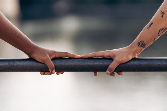 Fingers of people of different ethnicity touching each other on a railing