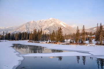 Winter landscape, with snow, trees and river passing through the rocky mountains in Canada