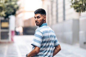 Serious man turning his head to face the camera as he walks in a city