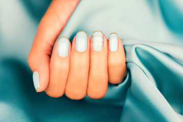 Beautiful female fingers with blue manicure and sparkles. Colored French manicure with sparkles.