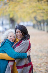 Fototapeta premium Enthusiastic senior women friends hugging in autumn park