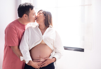 Husband kissing beautiful pregnant wife at home.