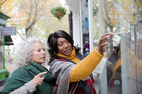 Senior women friends window shopping outside storefront