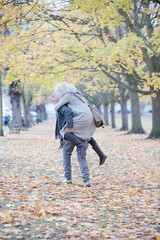 Fototapeta premium Senior man carrying woman on his back in autumn park