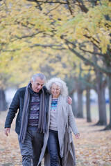 Fototapeta premium Affectionate couple hugging, walking among trees and leaves in autumn park